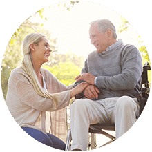 A daughter holding the hand of her elderly father in a wheelchair