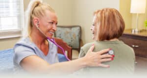 A nurse checking an elderly woman's heartbeat